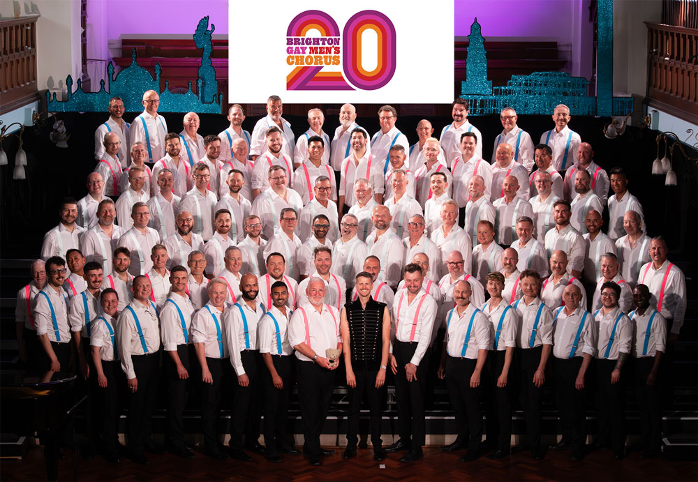 The Brighton Gay Men's Chorus in white shirts, black trousers and braces that make up the colours of the trans flag.
